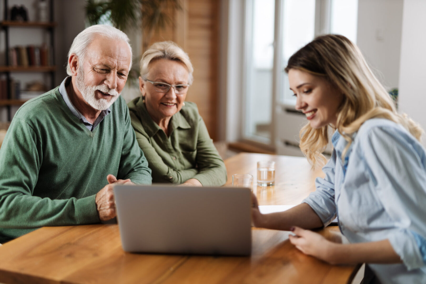 Happy mature couple  and their counselor communicating while using laptop on a meeting at home